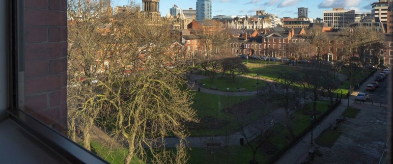 A view from a window of Leeds skyline and a quiet park.